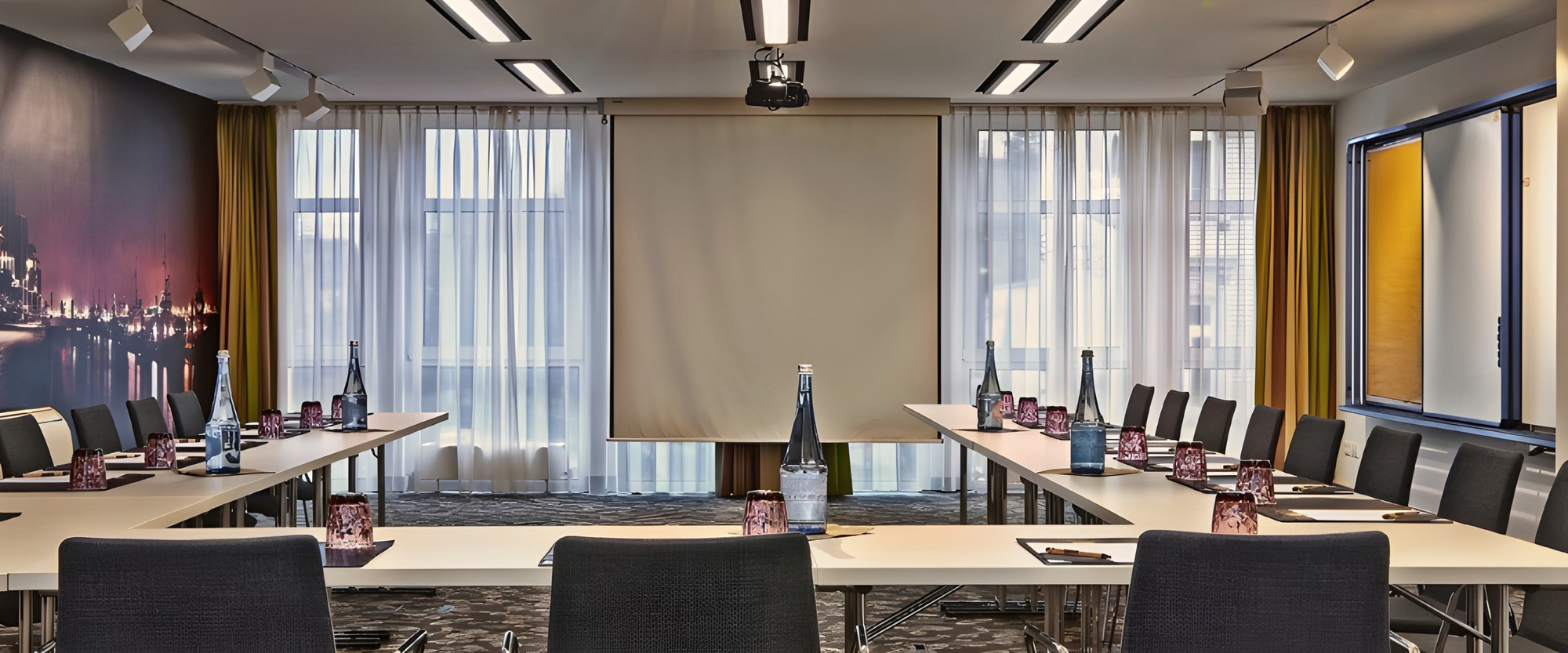 Moderner Tagungsraum im Hotel mit U-Bestuhlung, Präsentationsleinwand und professioneller Konferenztechnik