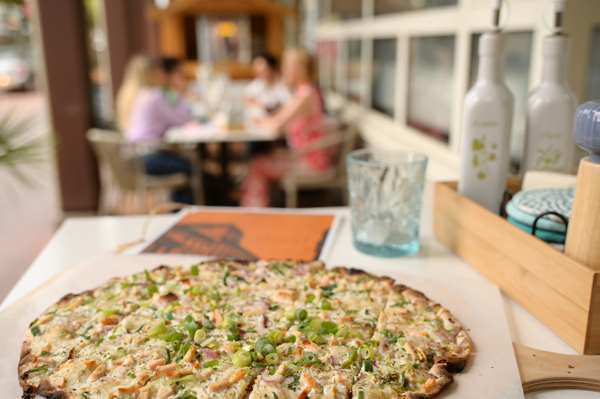 Flammkuchen auf einem Tisch im Hotelrestaurant mit Gästen im Hintergrund