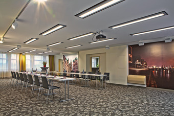 Moderner Tagungsraum im Hotel mit U-Bestuhlung, Präsentationsleinwand und professioneller Konferenztechnik