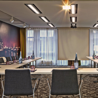 Moderner Tagungsraum im Hotel mit U-Bestuhlung, Präsentationsleinwand und professioneller Konferenztechnik